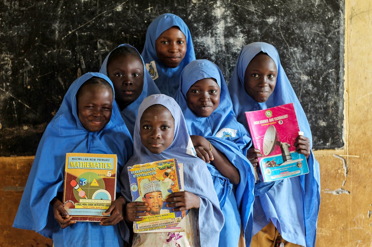 Girls in blue hijabs reading textbooks, emphasizing education and diversity.