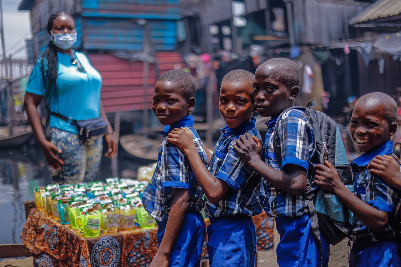 A group of cheerful African school kids in uniforms lined up together outdoors, exuding excitement and happiness.